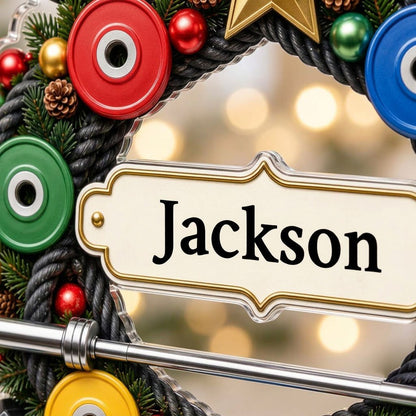 Acrylic ornament shaped around a gym wreath with dumbbells, bumper plates, barbell, and a name banner.