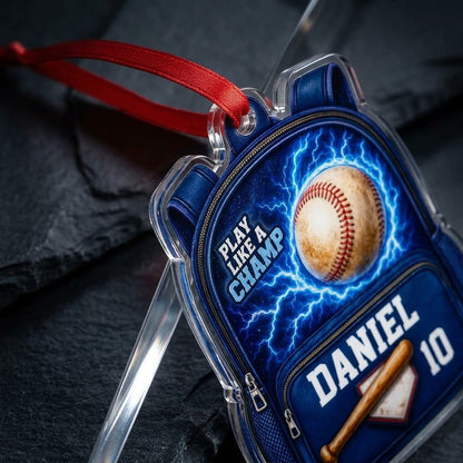 Backpack-shaped acrylic ornament with a baseball, blue lightning, a bat on home plate, and PLAY LIKE A CHAMP text.