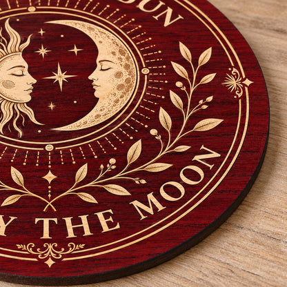 Round wooden sign with sun and crescent moon faces, stars, vines, and the quote Live by the Sun, Love by the Moon.