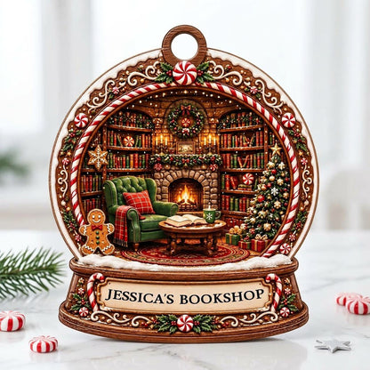 Snow globe ornament with candy-cane frame, cozy book-filled library, fireplace, tree, and 'JESSICA'S BOOKSHOP' nameplate