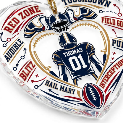 Heart-shaped glass ornament with back-view football player, gold stitched heart frame, football, and play diagram elemen