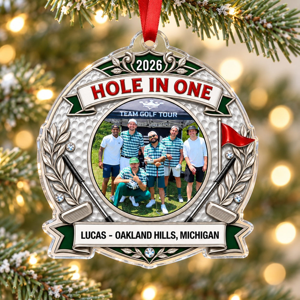 Silver trophy-style golf ornament with laurel branches, crossed clubs, red flag, 2026 and HOLE IN ONE, plus a circular p