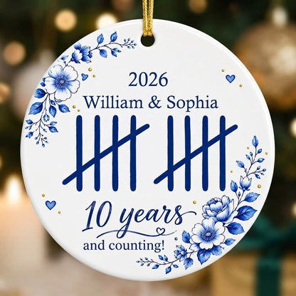 White round ceramic ornament with blue florals, tally marks, and 'years and counting!' plus names and year