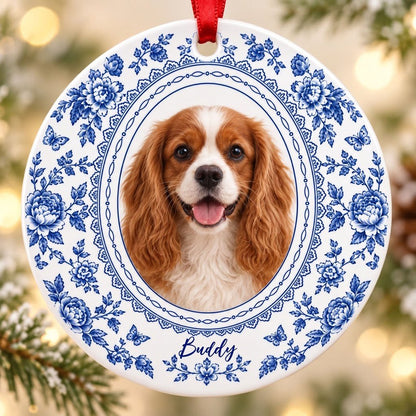 Round white ceramic ornament with blue Delft floral and butterfly pattern around an oval dog photo and name.