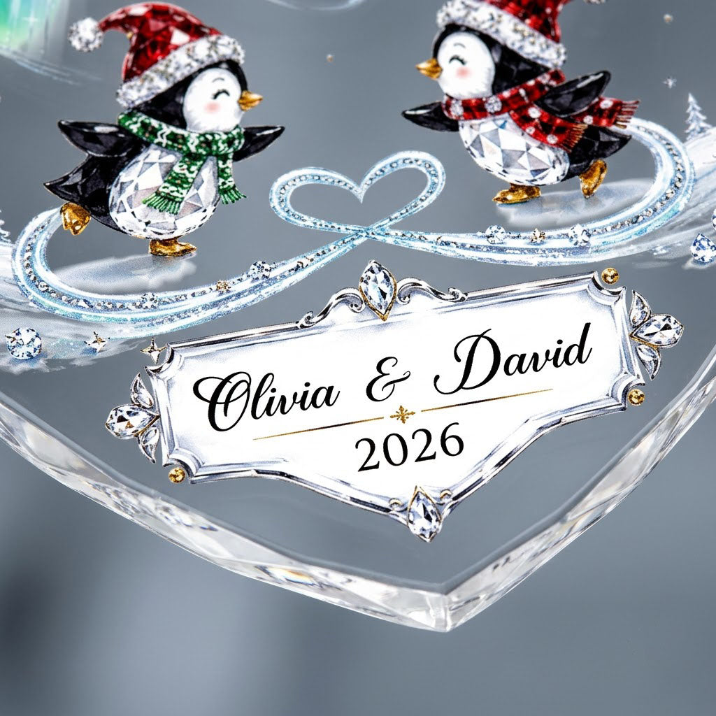 Heart glass ornament with two ice-skating penguins under green and blue aurora with names and date.