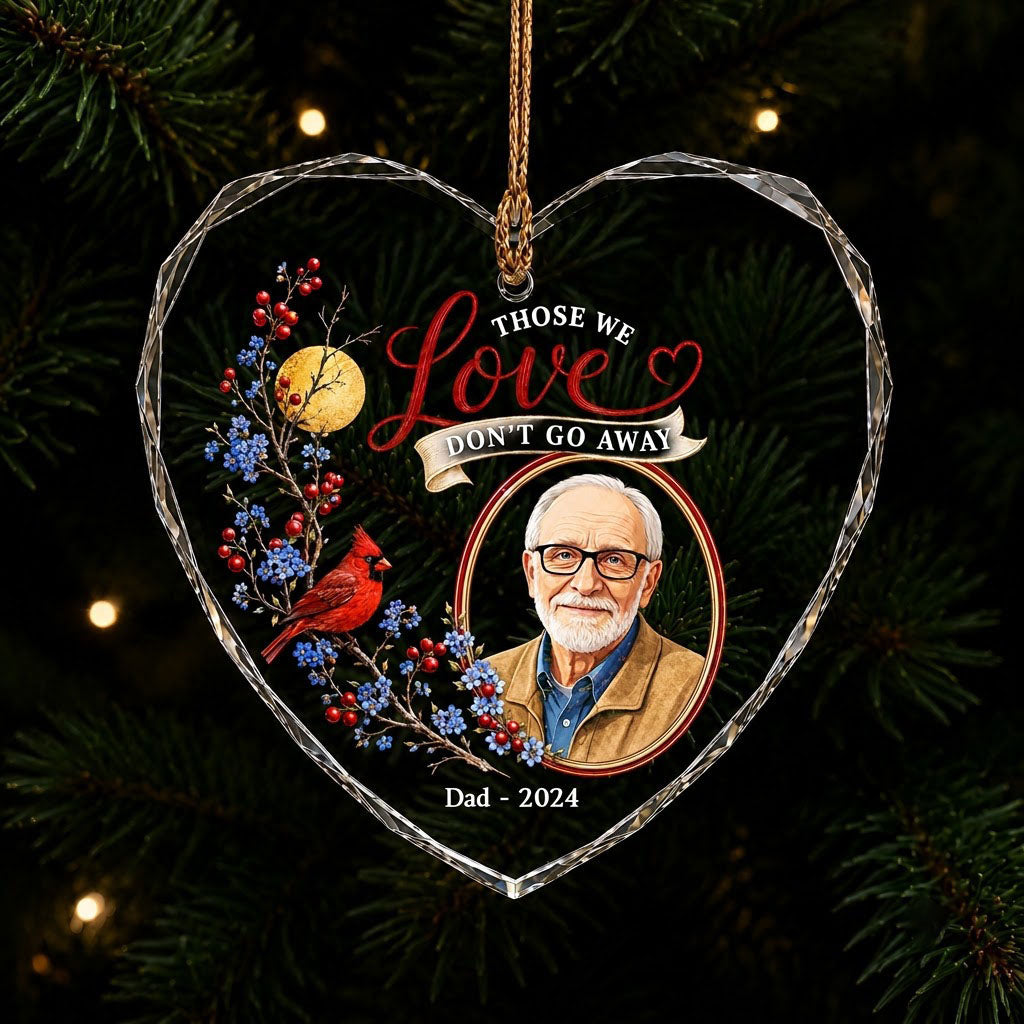 Heart-shaped glass ornament with a red cardinal, golden moon, photo frame and the quote 'THOSE WE Love DON'T GO AWAY'.