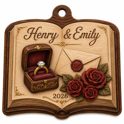 Open book wood ornament with a ring box, red roses, wax-sealed envelope, and custom names and year.