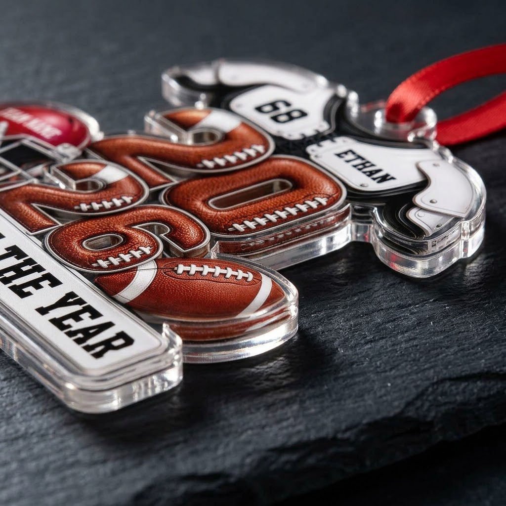 Acrylic ornament shaped like football gear with 2026 numbers, red helmet, ball and 'Rookie of the Year' nameplate.