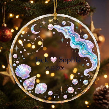 Round glass ornament with iridescent seashells, pearls, crescent moon, and a heart constellation with names and date.