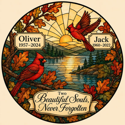 Two red cardinals with a glowing sun over a mountain lake and pine trees, framed by autumn oak leaves on a round suncatc