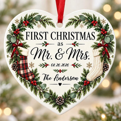 Heart ornament with greenery border, two stockings on bows, and 'FIRST CHRISTMAS as Mr. & Mrs.' text.