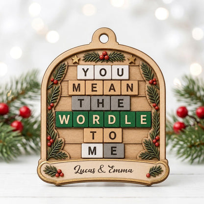 Arch wood ornament with “You Mean The Wordle To Me” letter tiles, evergreen sprigs with red berries, gold stars, and cou