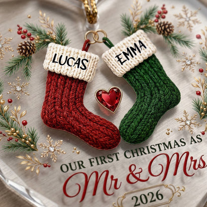 Heart-shaped glass ornament with red and green stockings hanging from gold rings and a red gemstone heart