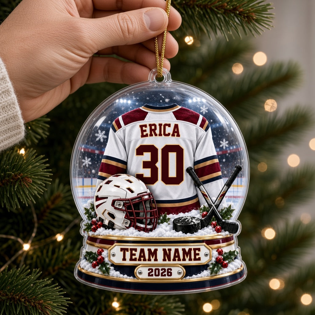 Acrylic snow globe ornament with hockey jersey, helmet, crossed sticks, puck, snowflakes and holly accents.