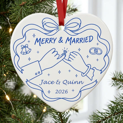 White heart ceramic ornament with blue line art: pinky promise hands, bells, rings, and MERRY & MARRIED text.