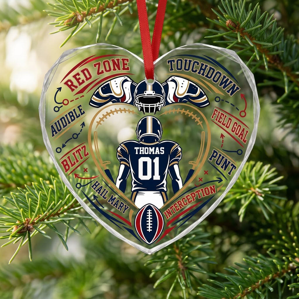 Heart-shaped glass ornament with back-view football player, gold stitched heart frame, football, and play diagram elemen