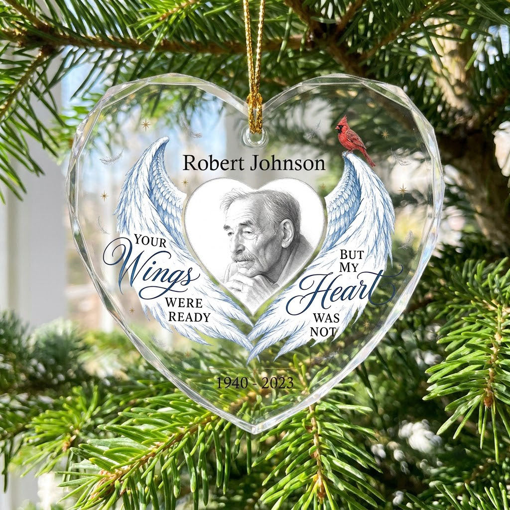 Heart-shaped glass ornament with blue angel wings, red cardinal, and a memorial quote with name and years.