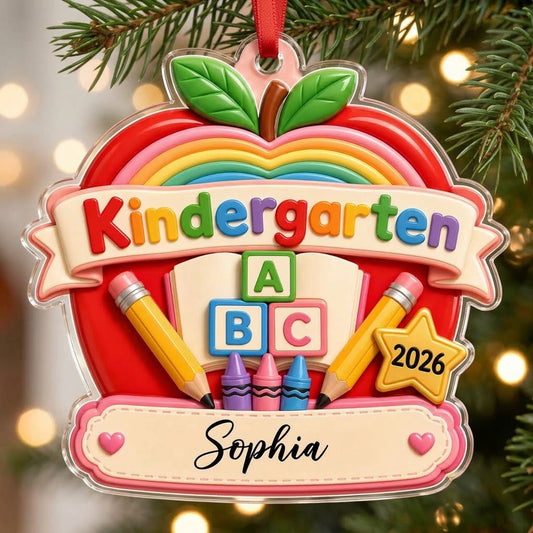 Red apple acrylic ornament with 'Kindergarten 2026', rainbow, ABC blocks, crayons, pencils, star badge, and a name banne