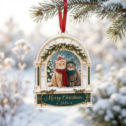 Arched window acrylic ornament with pine garland, gold bells, two cats in winter hats and scarves, and a green banner fo