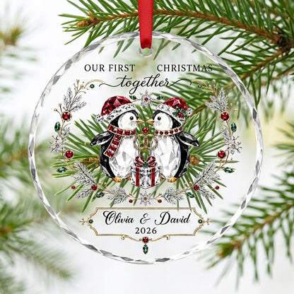 Penguin couple in Santa hats hold gold rings beneath a heart, framed by a pine and gem wreath with a gift box.