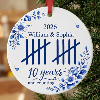 White round ceramic ornament with blue florals, tally marks, and 'years and counting!' plus names and year