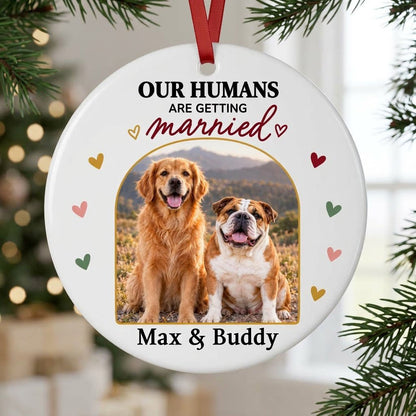Round ceramic ornament with arch dog photo, “OUR HUMANS ARE GETTING married” text, and colorful heart accents.