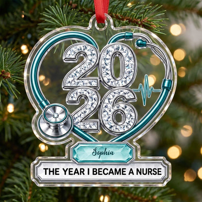 Clear acrylic ornament with a teal stethoscope heart, diamond 2026 numerals, teal ECG wave, and a personalized name bann