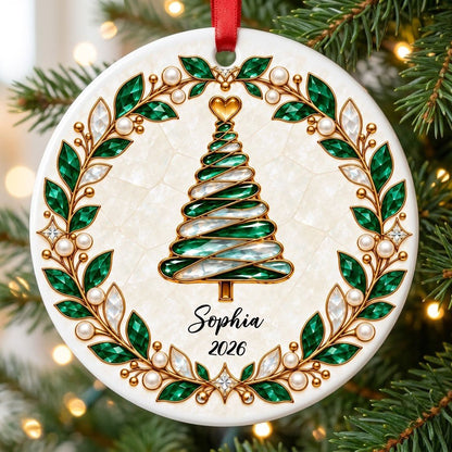 Round ceramic ornament with an emerald jeweled spiral Christmas tree and gold filigree wreath on cream.