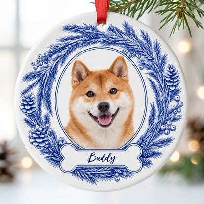 Round ceramic ornament with blue pine wreath, oval dog photo frame, and a blue-outlined bone at the bottom.