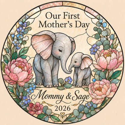 Round stained-glass suncatcher of mother and baby elephants touching trunks amid pink peonies and blue flowers.