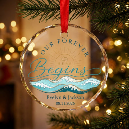 Round glass ornament with gold sun, interlocking rings, teal ocean waves, and 'OUR FOREVER HERE Begins' text.