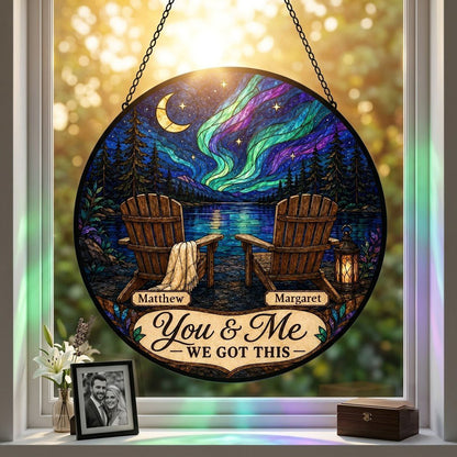 Round stained-glass style suncatcher with aurora, crescent moon, pine trees, lake, two chairs and a lantern.