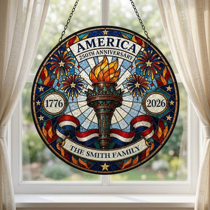 Round stained glass suncatcher with a central torch, fireworks, stars, and a red, white and blue ribbon.