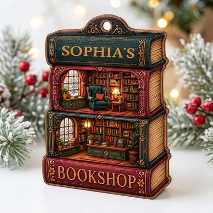 Custom-cut ornament of stacked books showing cozy bookshop rooms, BOOKSHOP text, and a personalized name.
