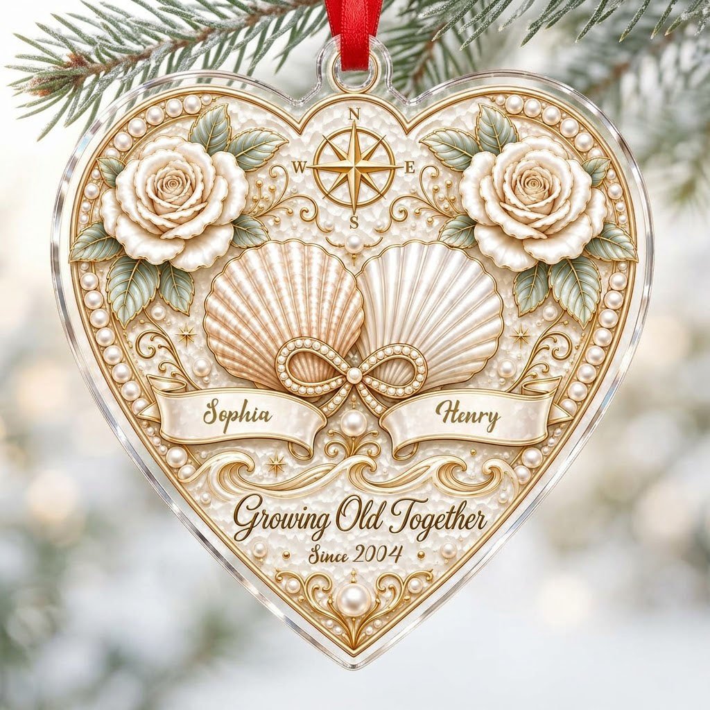 Heart-shaped clear acrylic ornament with seashells, pearl infinity symbol, compass star, and two name ribbons.