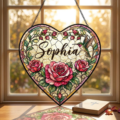 Heart stained-glass suncatcher with pink and red roses, a right-side hummingbird, and a multi-colored border.