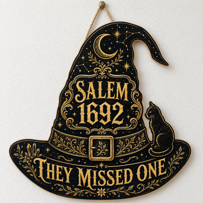 Witch hat-shaped wooden sign with 'SALEM 1692 THEY MISSED ONE', crescent moon, stars, filigree, and a black cat on the b