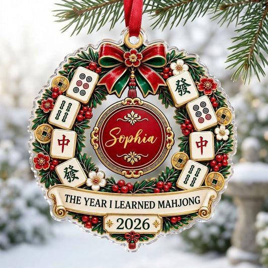 A clear acrylic wreath ornament with Mahjong tiles, red bow, gold coins, and the text THE YEAR I LEARNED MAHJONG.