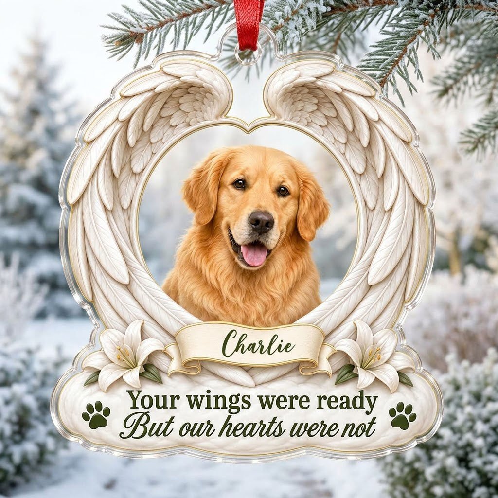 Clear acrylic angel wings ornament with a circular dog photo, white lilies, a dark green paw print, and a name banner.