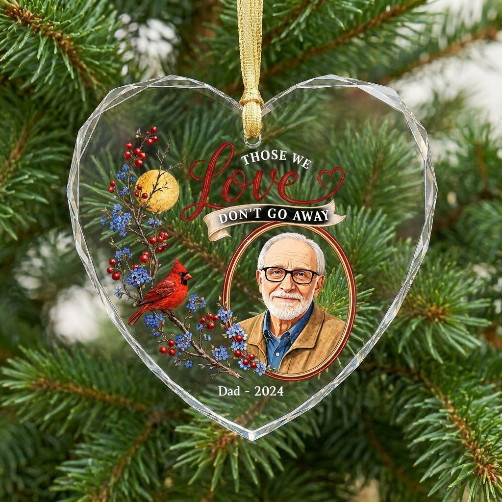 Heart-shaped glass ornament with a red cardinal, golden moon, photo frame and the quote 'THOSE WE Love DON'T GO AWAY'.
