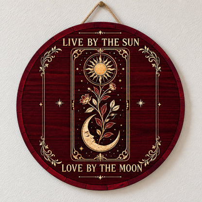 Round wooden sign with tarot-style sun and sleeping moon, floral vine, stars, and the words Live by the Sun, Love by the