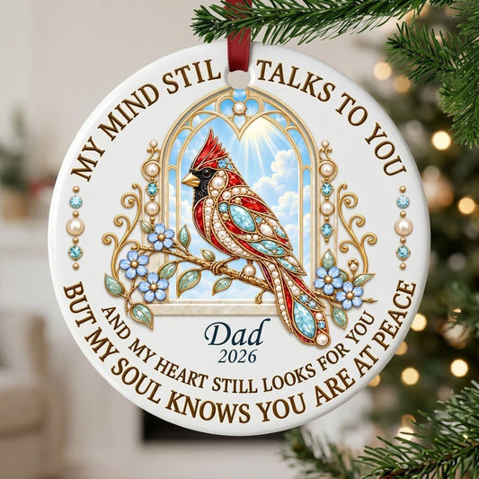 Round ceramic ornament with a red cardinal by a gold arched window, blue flowers, pearls, and a faux marble border.