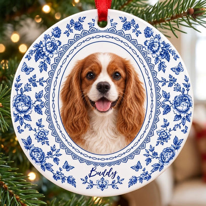 Round white ceramic ornament with blue Delft floral and butterfly pattern around an oval dog photo and name.