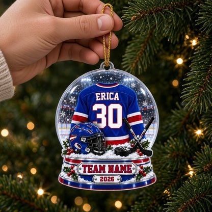 A custom-cut snow globe acrylic ornament with hockey jersey, helmet, crossed sticks, puck, and holly on the base.