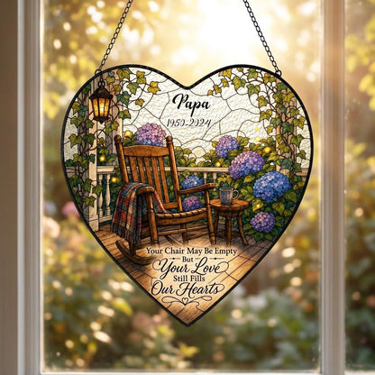 Heart stained glass suncatcher with empty porch rocking chair, lantern, ivy, and purple and blue hydrangea bushes.