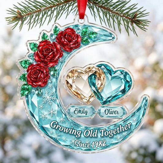 Custom-cut acrylic ornament of a faceted crescent moon with red roses, snowflakes, and two intertwined crystal hearts.