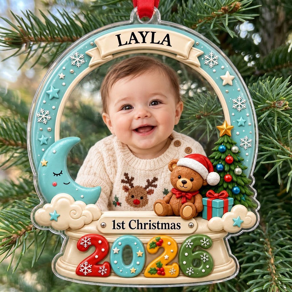 Acrylic snow-globe ornament with baby photo, "1st Christmas", teddy bear, moon, clouds, and big 2026 at the base.