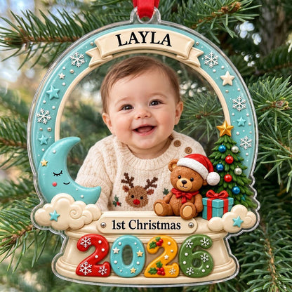 Acrylic snow-globe ornament with baby photo, "1st Christmas", teddy bear, moon, clouds, and big 2026 at the base.