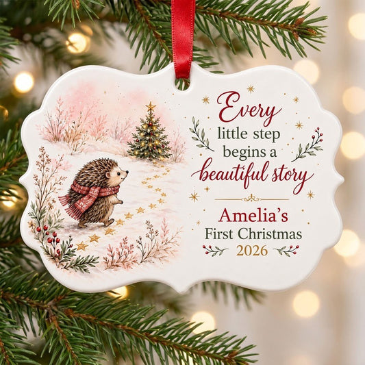 Scalloped ceramic ornament with hedgehog in red plaid scarf walking toward a decorated Christmas tree in the snow.