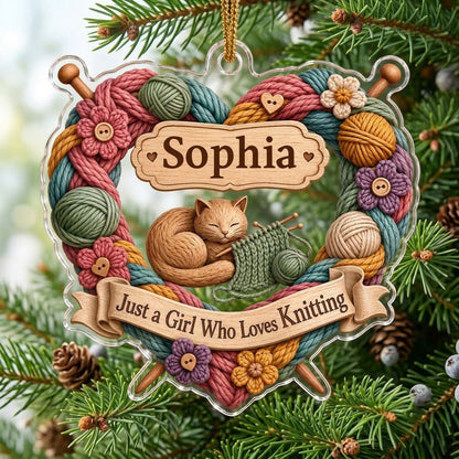 Heart-shaped acrylic ornament with yarn wreath, knitting needles, brown cat and "Just a Girl Who Loves Knitting" text.